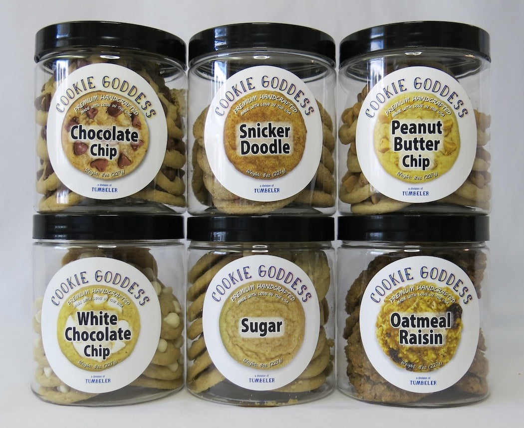 Six jars of 'Cookie Goddess' cookies with various flavors on a white background
